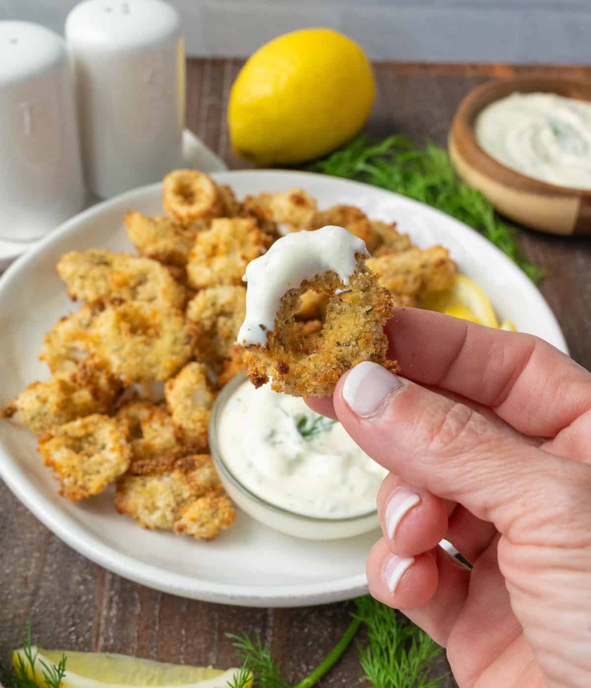 A fried calamari ring dipped in dill sauce.