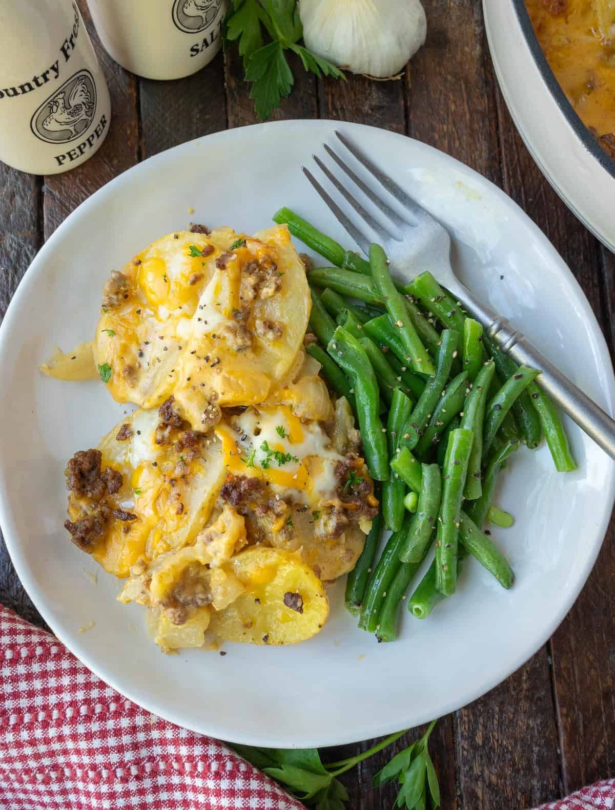 A serving of hamburger potato casserole with a side of green beans.