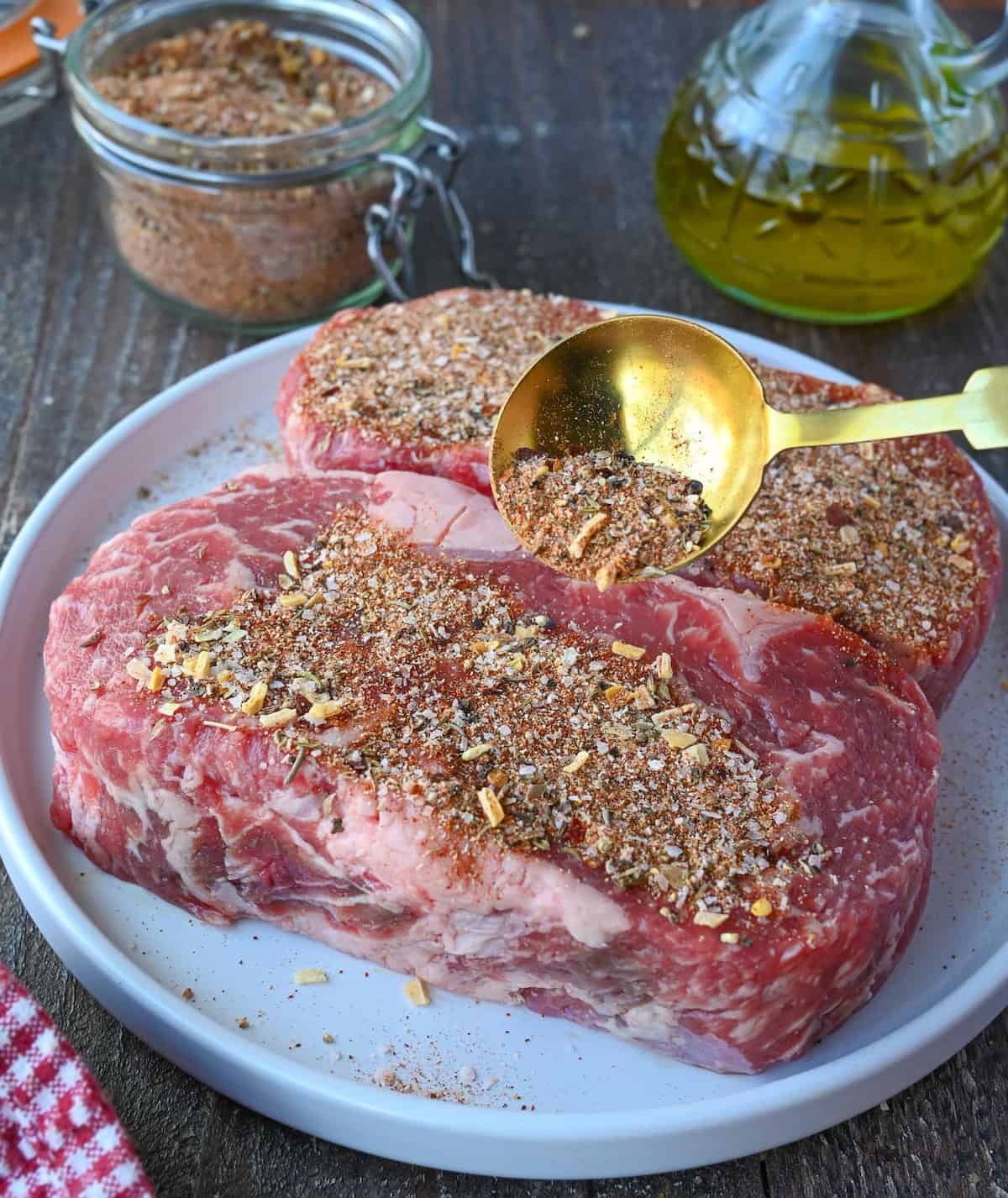 Beef rub sprinkled on top of rib eye steak.