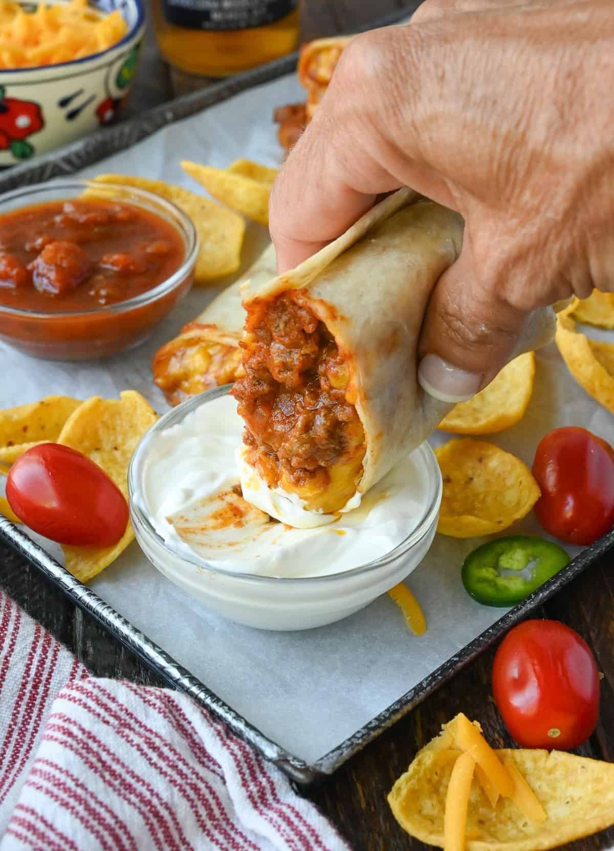 Dipping a chili cheese burrito in a dish of sour cream.