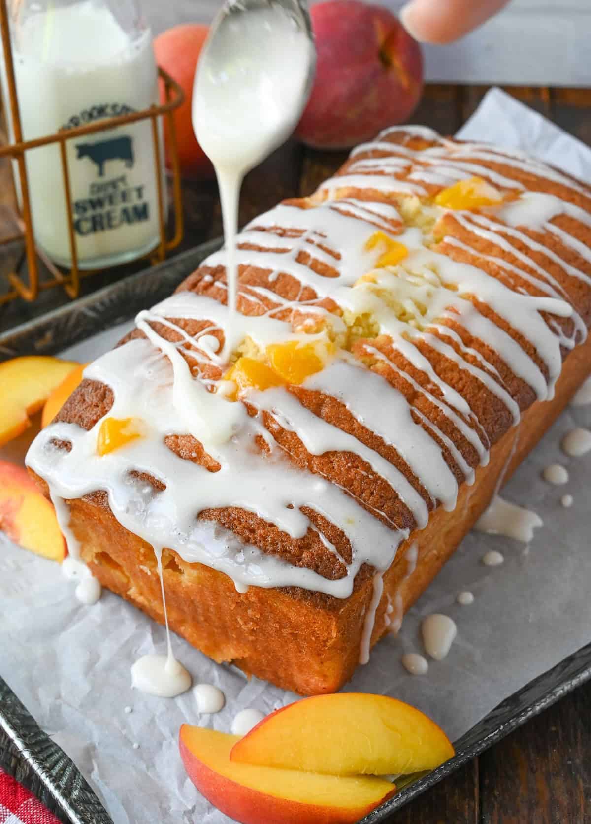 Vanilla glaze being drizzled over peach cake.