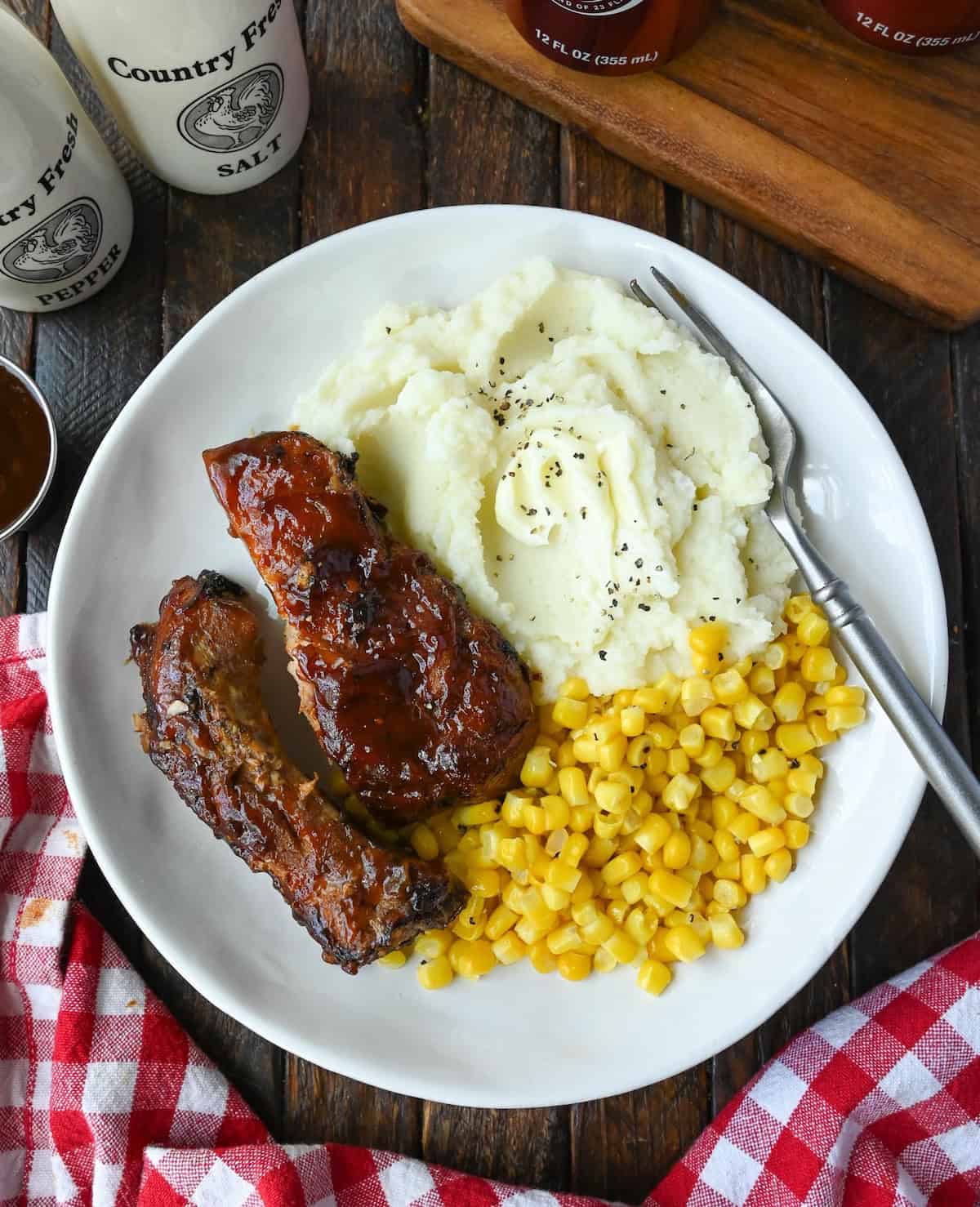 Dr pepper ribs on a plate with mashed potatoes and corn.