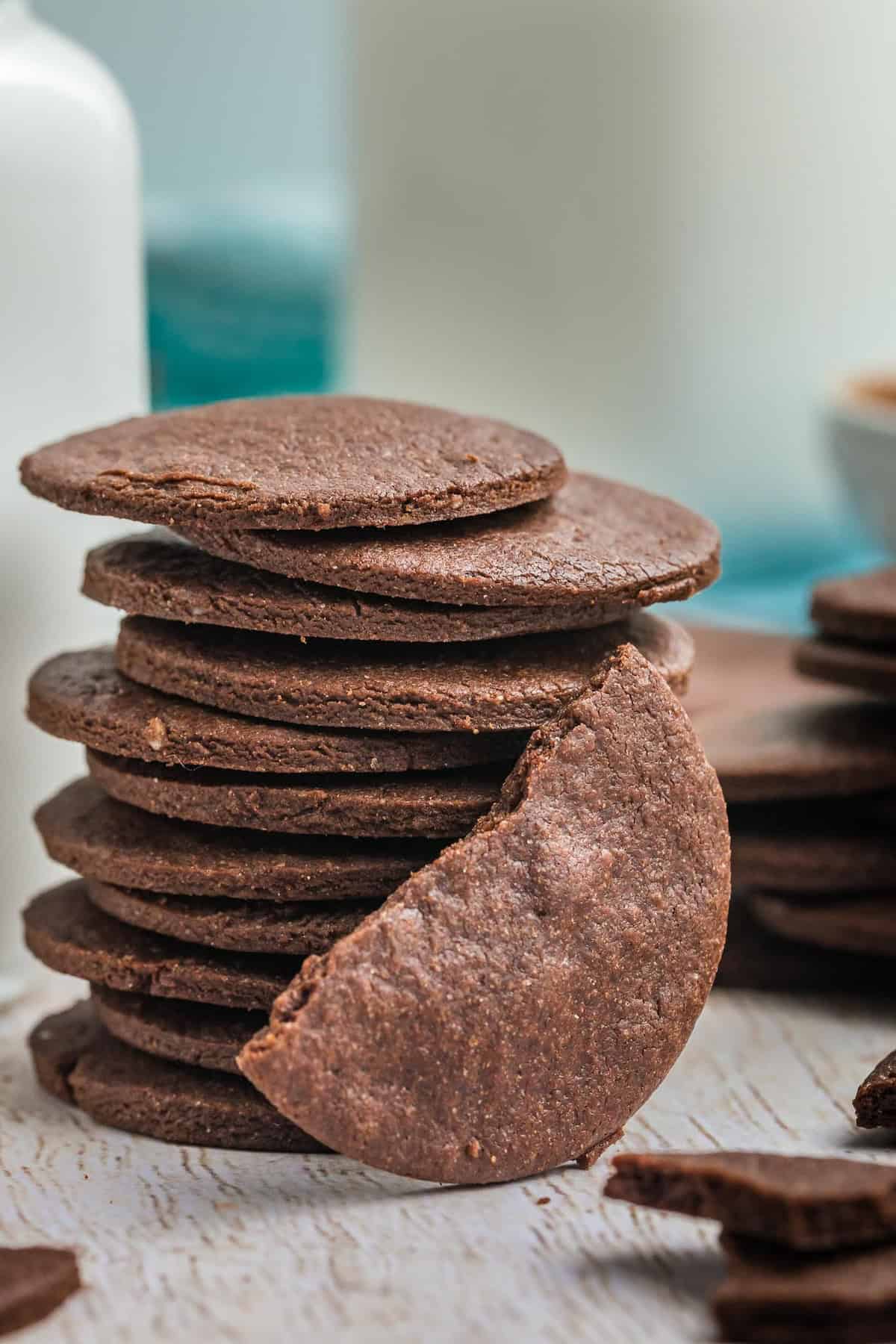 A stack of chocolate wafer cookies with one broken in half and leaning against the stack.