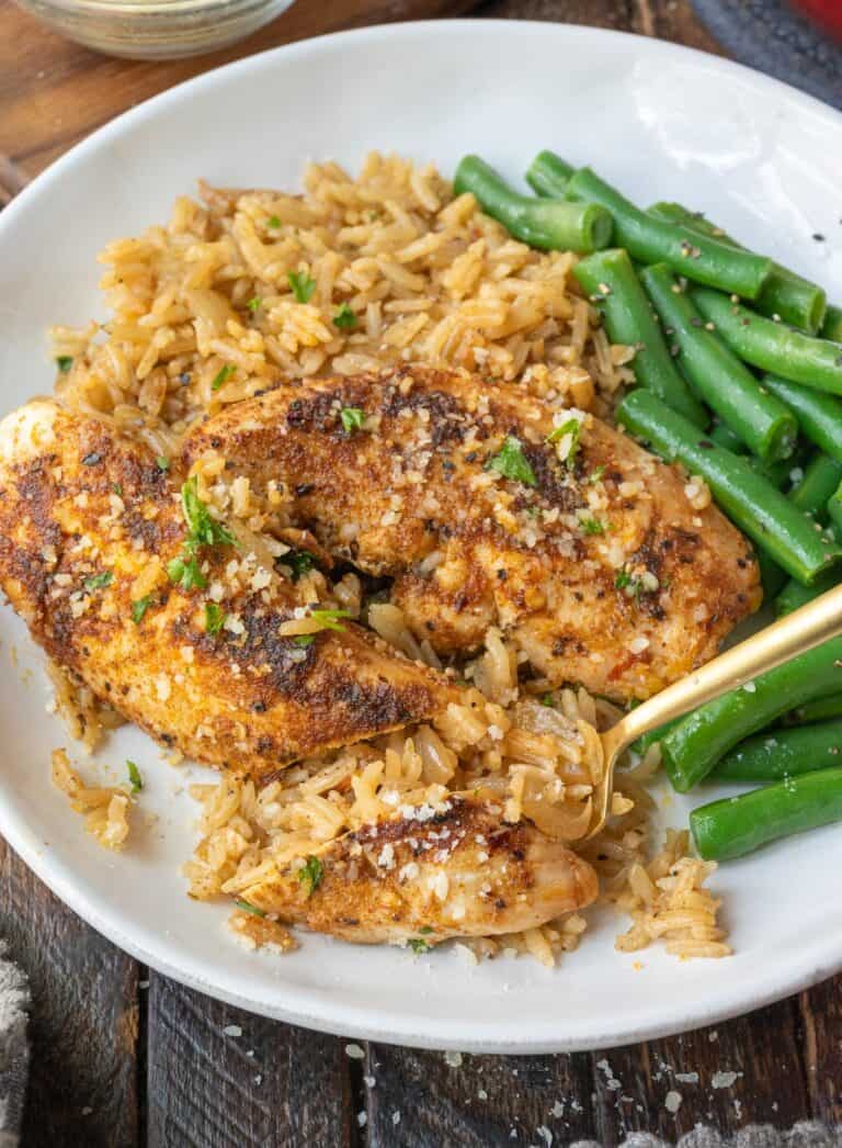 Close up of garlic chicken rice bake on a plate with green beans.