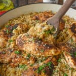 Close up of a wooden spoon scooping up chicken and rice bake.