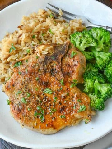 A plate of pork chop and rice casserole with broccoli.