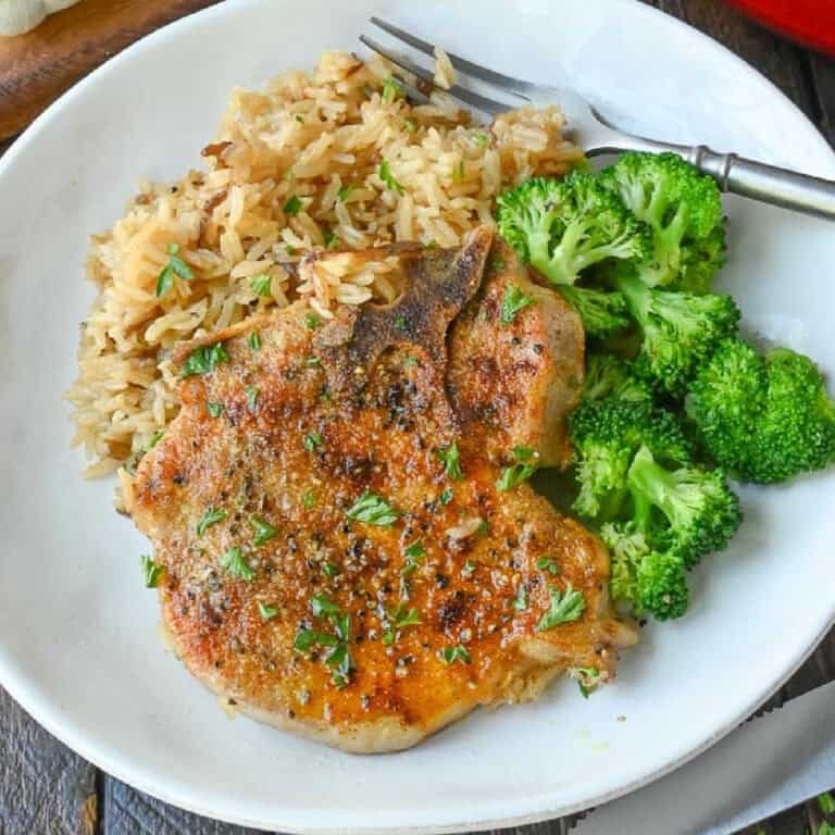 A plate of pork chop and rice casserole with broccoli.