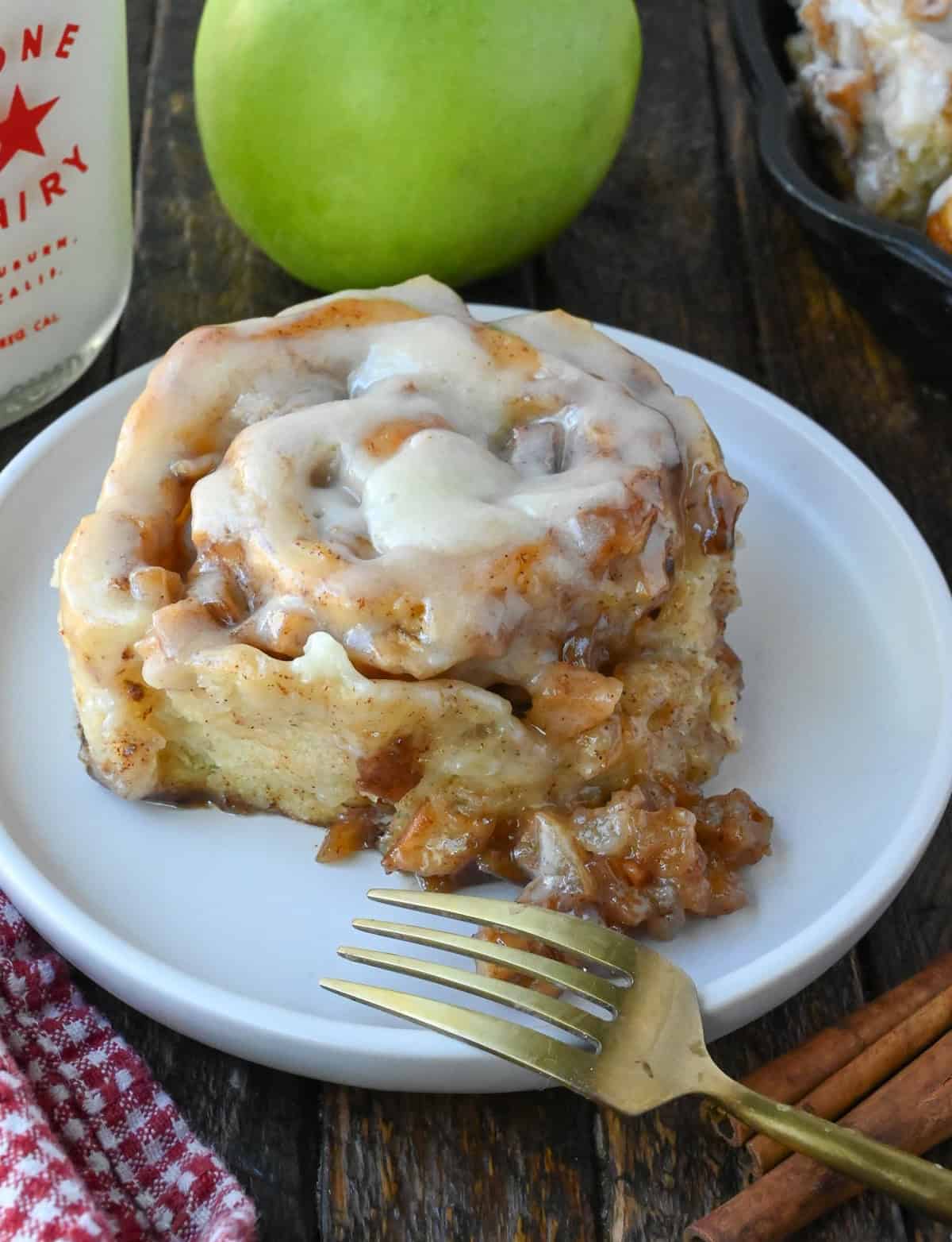 apple pie cinnamon roll on a white plate with a fork.