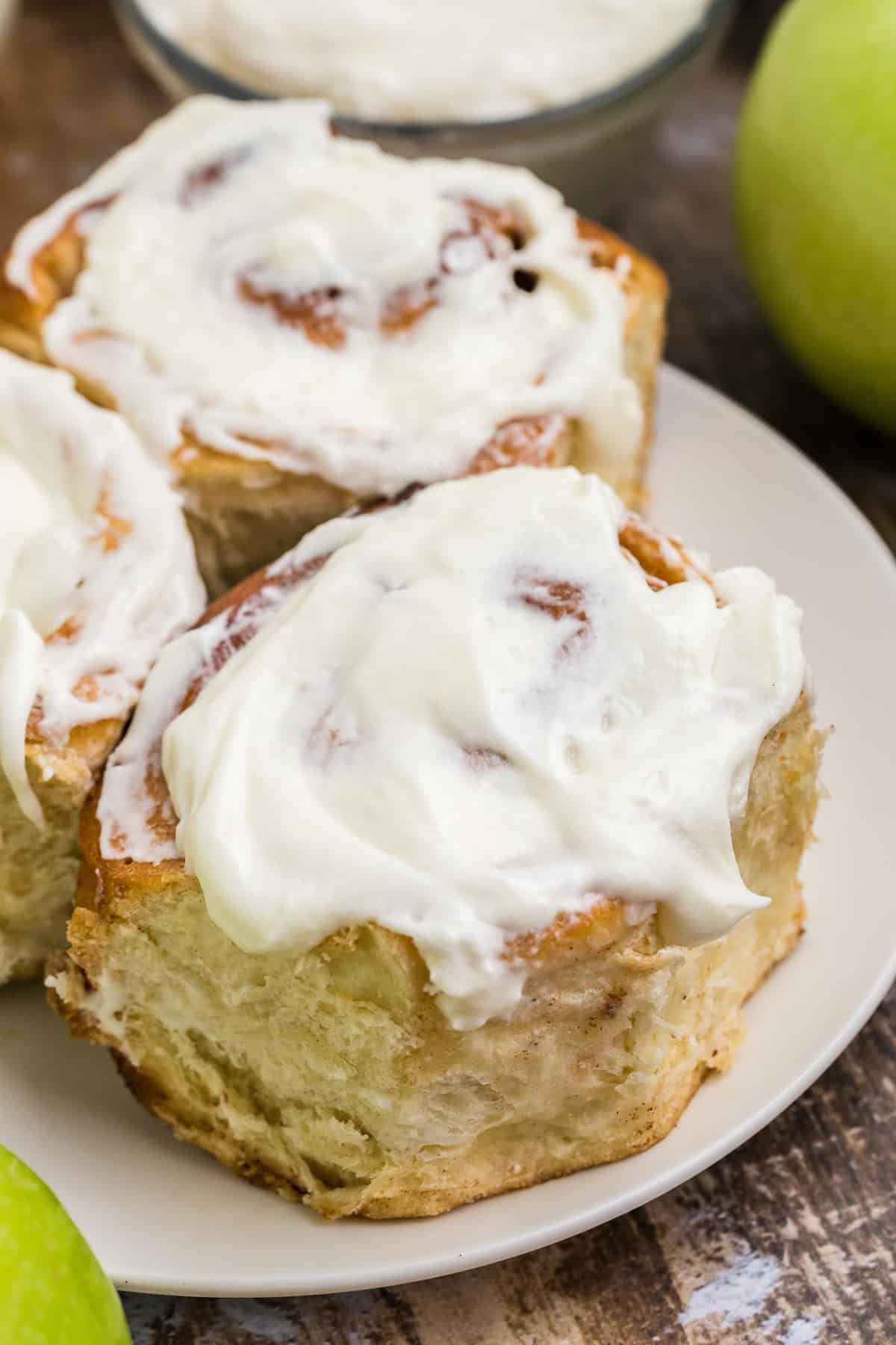 Close up of apple cinnamon rolls with icing on a plate.