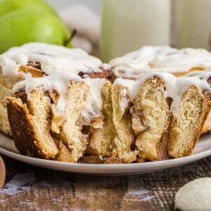 Side view of a frosted apple cinnamon roll cut in half.