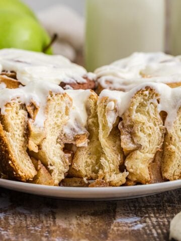 Side view of a frosted apple cinnamon roll cut in half.