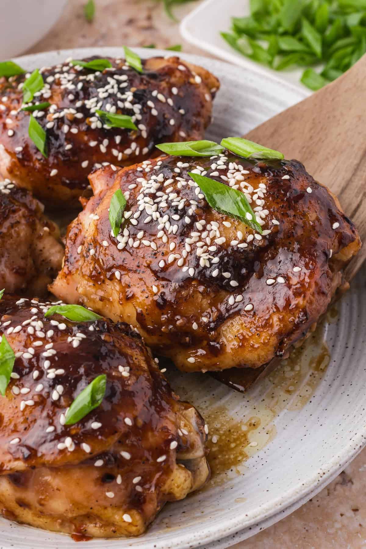 Using a spatula to lift up a piece of perfectly cooked baked teriyaki chicken.