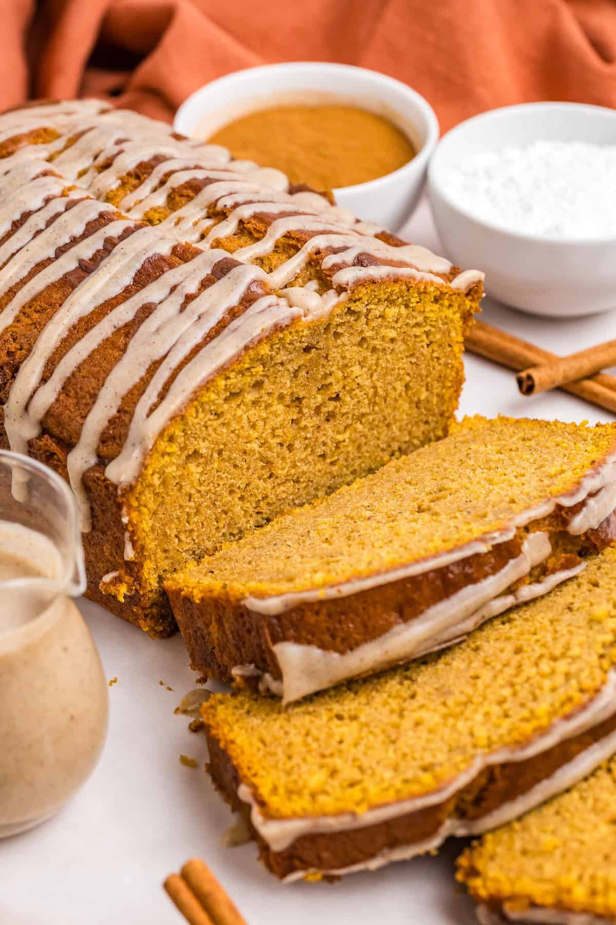 A loaf of pumpkin loaf cake with several slices cut out of it.