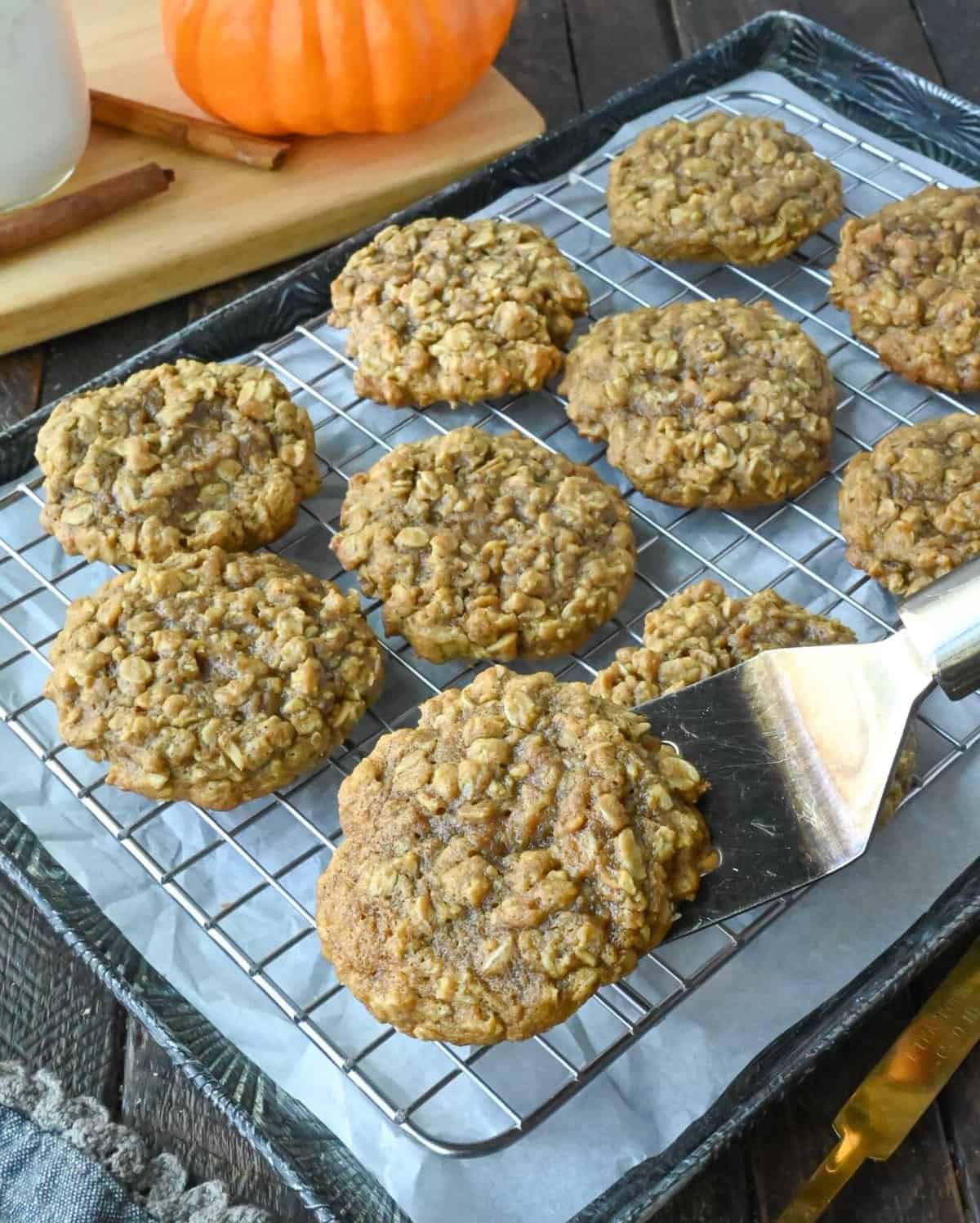 Using a spatula to lift a pumpkin cookie from a cooling rack.