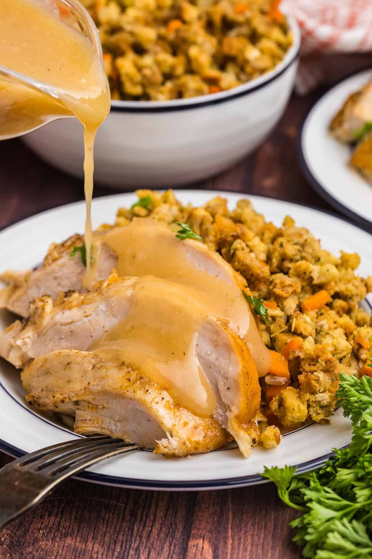 Pouring gravy over a plate with crock pot turkey and stuffing.