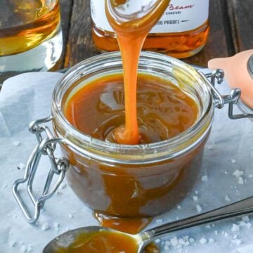 Spooning bourbon caramel sauce out of a glass container.