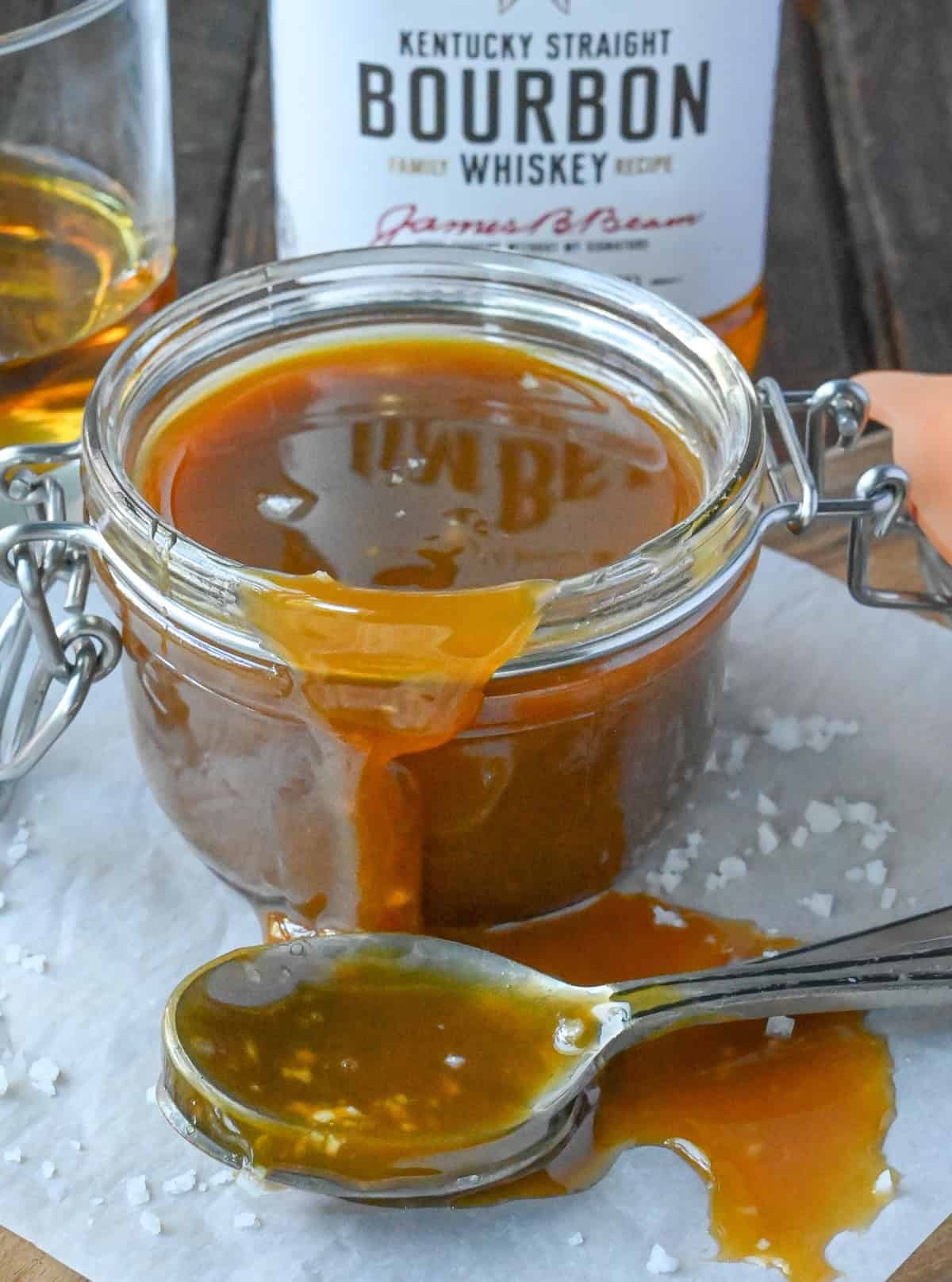 A glass container full of caramel bourbon sauce.