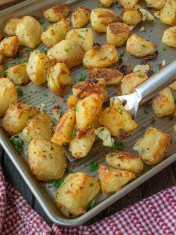 A spatula scooping up sone crispy roasted potatoes.