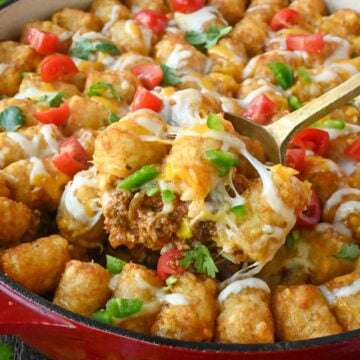 Close up of a scoop of tater tot casserole being taken from a baking dish.