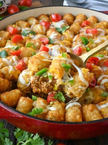 Close up of a scoop of tater tot casserole being taken from a baking dish.