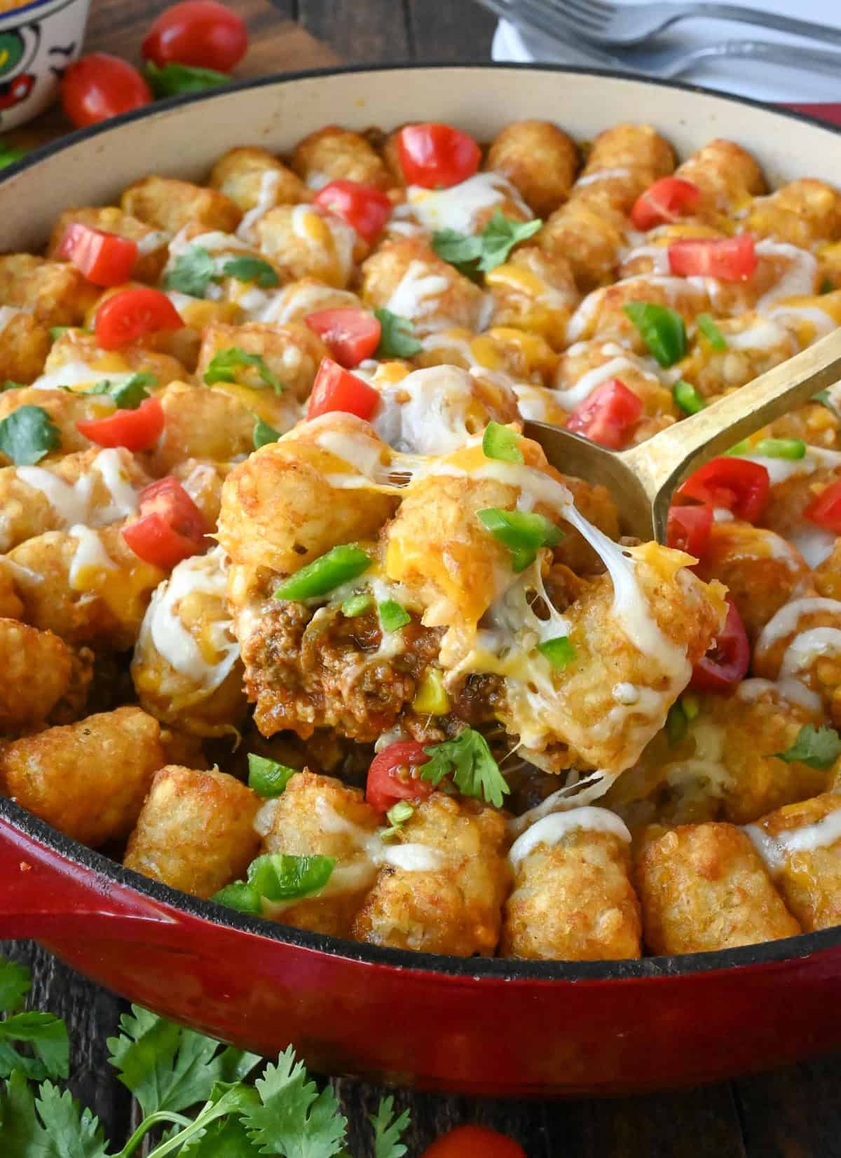 Close up of a scoop of tater tot casserole being taken from a baking dish.