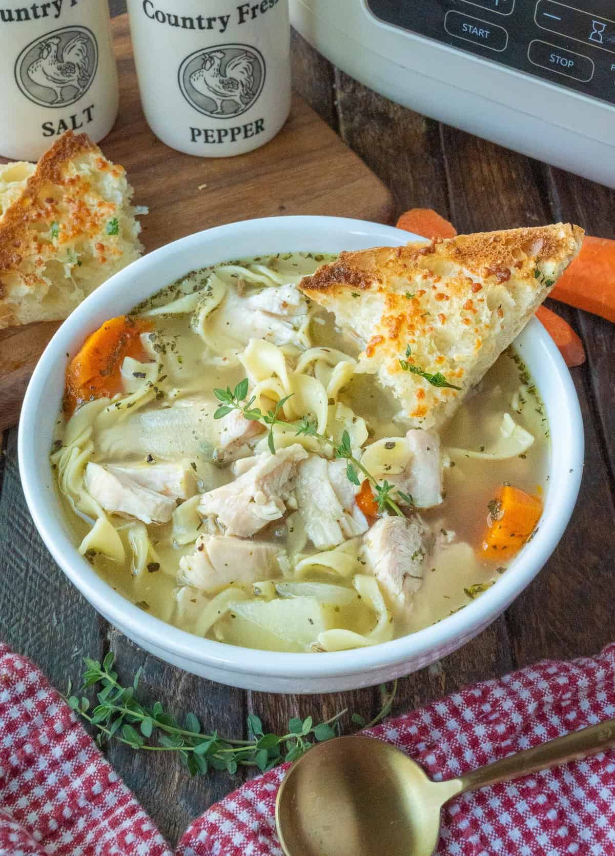 Dipping a piece of toasted ciabatta bread into a bowl of turkey noodle soup.