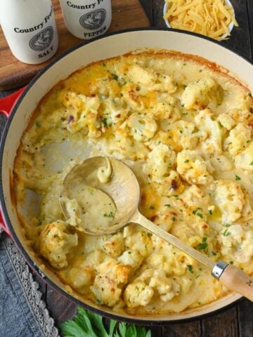 Cauliflower au gratin in a skillet with a spoon.