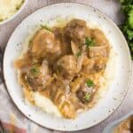 Top down view of a plate of meatballs and gravy with mashed potatoes.