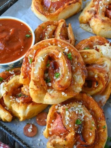 Pepperoni pinwheels on a platter with a dish of marinara sauce.