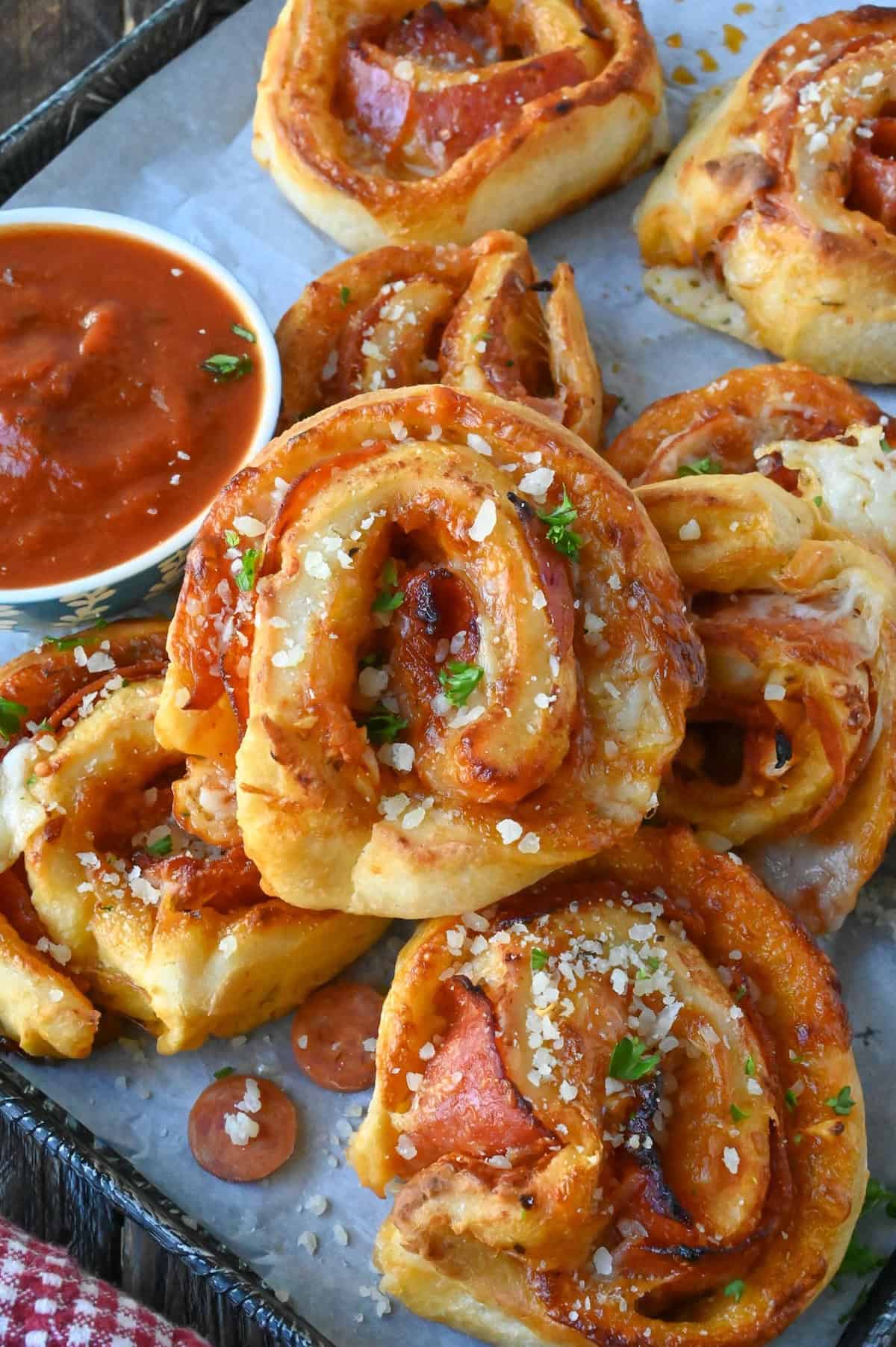 Pepperoni pinwheels on a platter with a dish of marinara sauce.