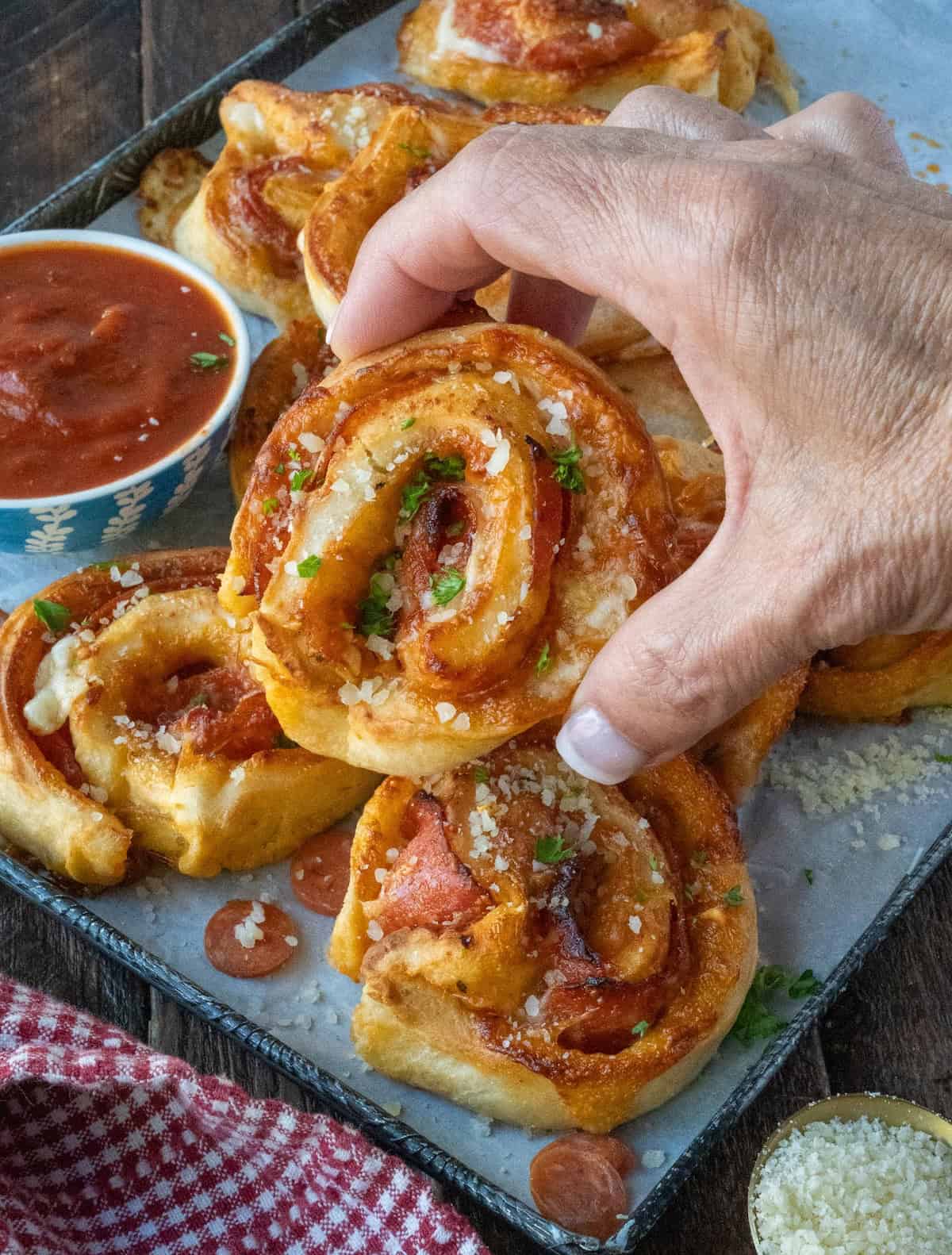 Holding up a golden brown pepperoni pizza pinwheel.