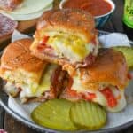 A plate with three stacked hot Italian sliders.