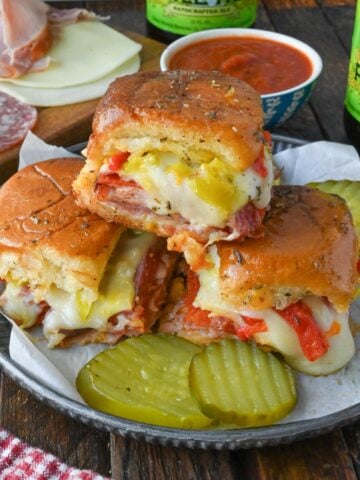 A plate with three stacked hot Italian sliders.