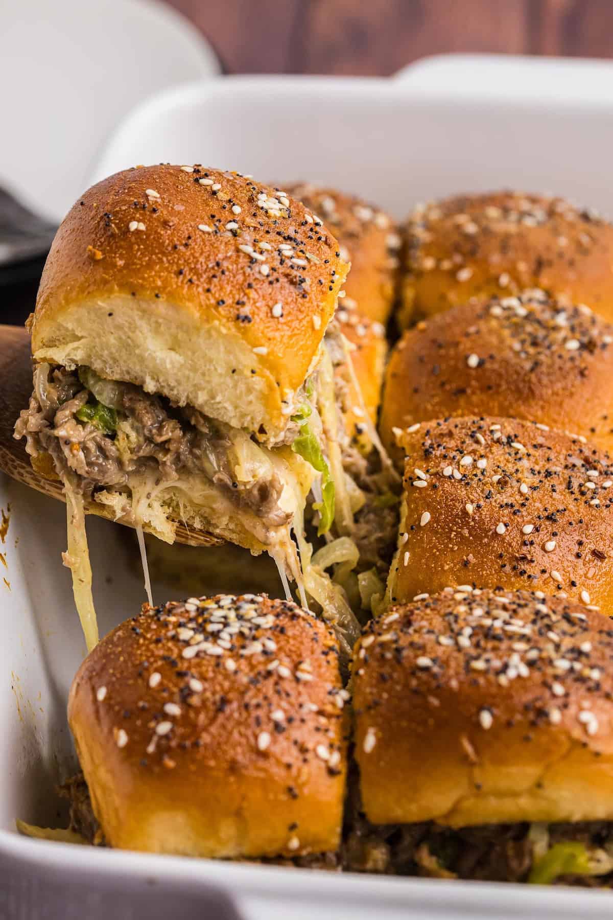 Lifting a slider from a casserole dish of other sliders.