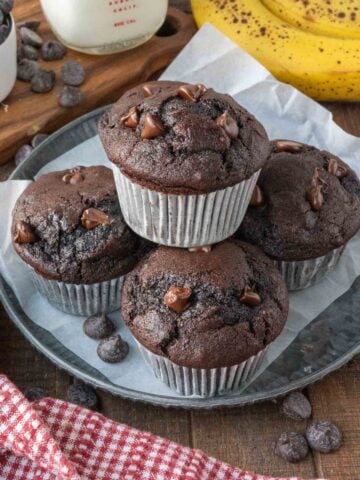 A plate of 5 chocolate banana muffins arranged in a stack.