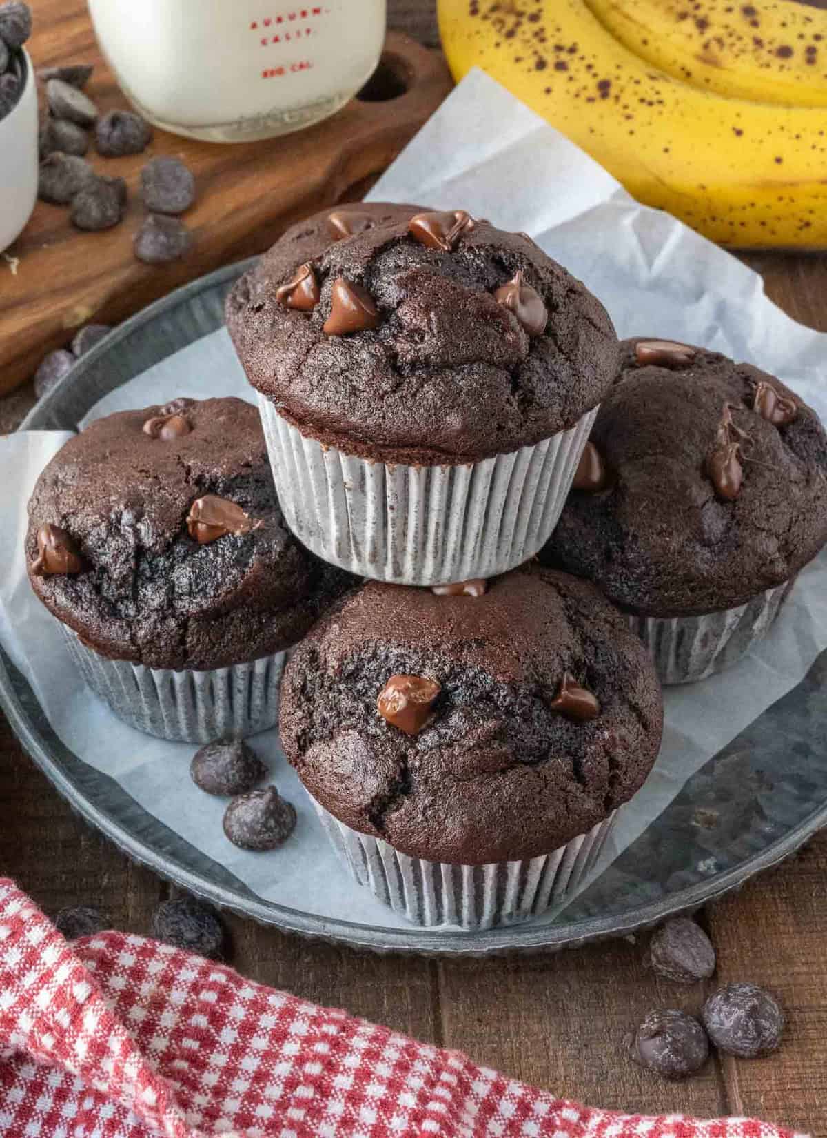 A plate of 5 chocolate banana muffins arranged in a stack.