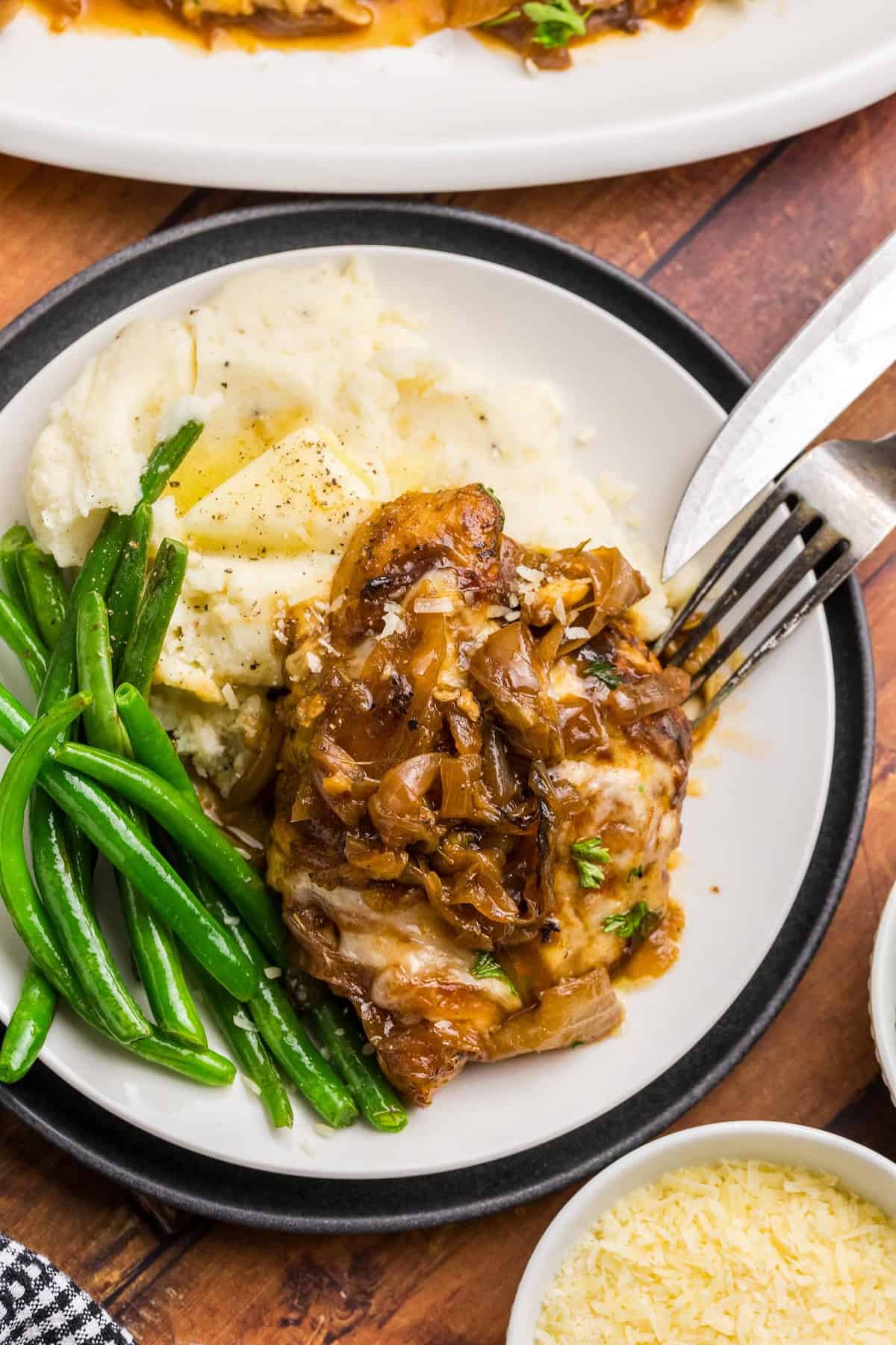 A plate with mashed potatoes, green beans, and french onion chicken bake.