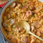 Cheesy sausage pasta skillet with a serving spoon.