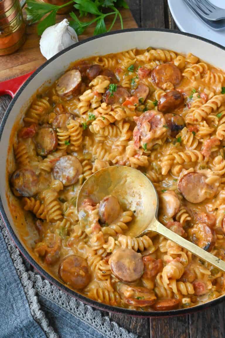Cheesy sausage pasta skillet with a serving spoon.