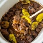 Mississippi steak bites in the slow cooker with a serving spoon scooping some out.