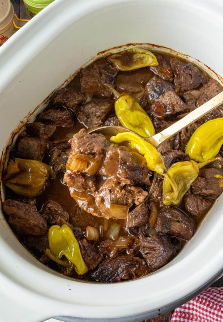Mississippi steak bites in the slow cooker with a serving spoon scooping some out.