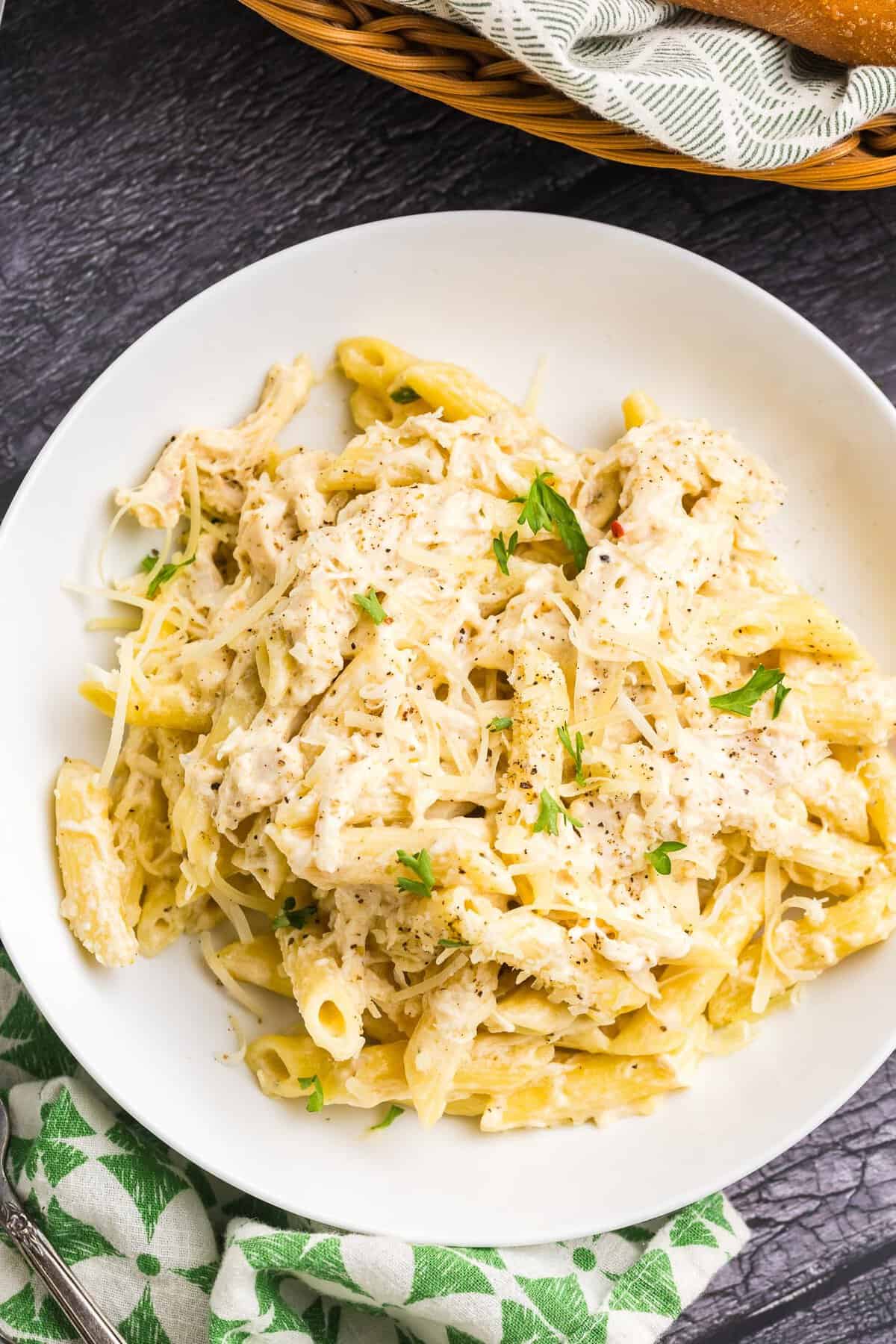 A plate of olive garden chicken pasta garnished with herbs and cheese.