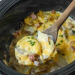 Ham and potatoes being scooped from a slow cooker.