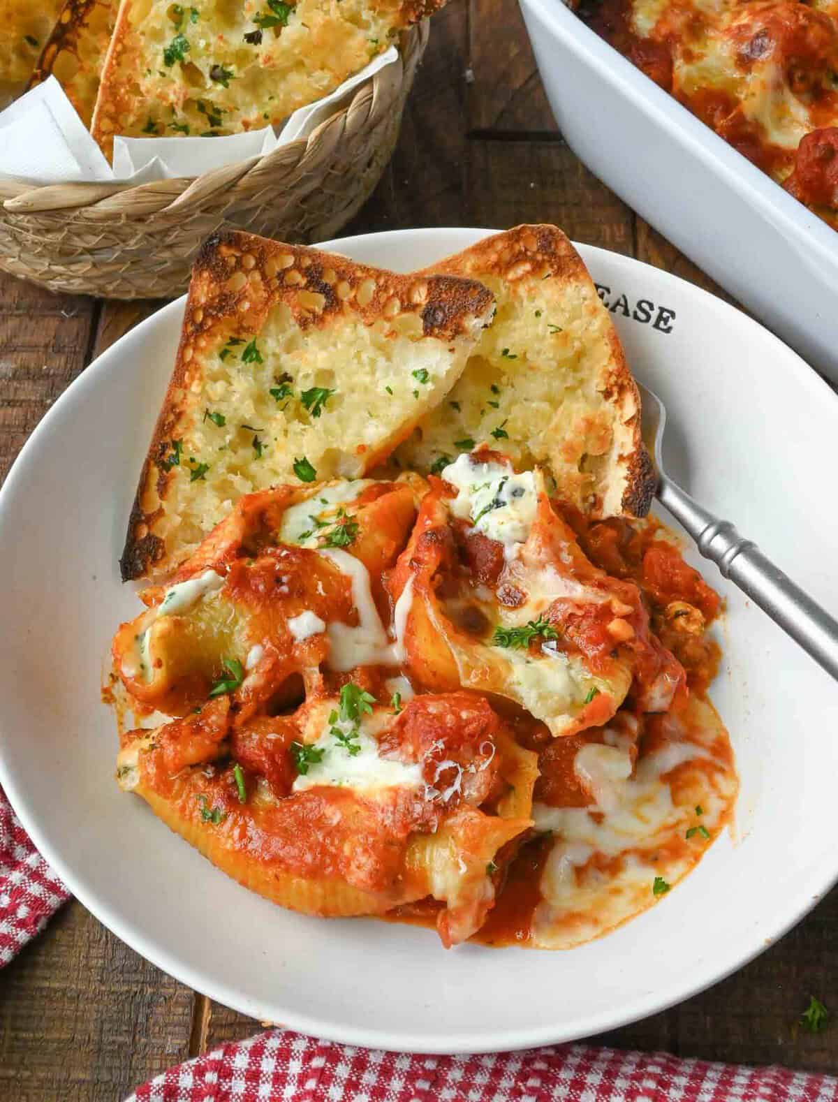 A plate of cheese stuffed shells with two slices of garlic bread.