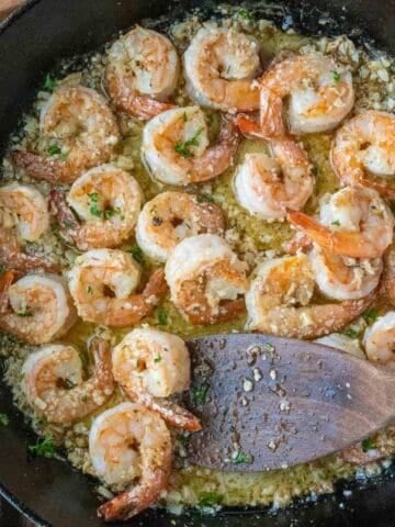 Using a spatula to stir copycat shrimp scampi in a skillet.