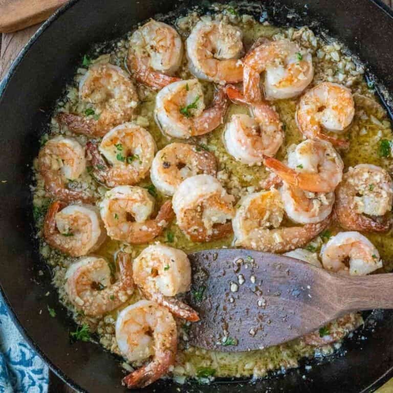 Using a spatula to stir copycat shrimp scampi in a skillet.