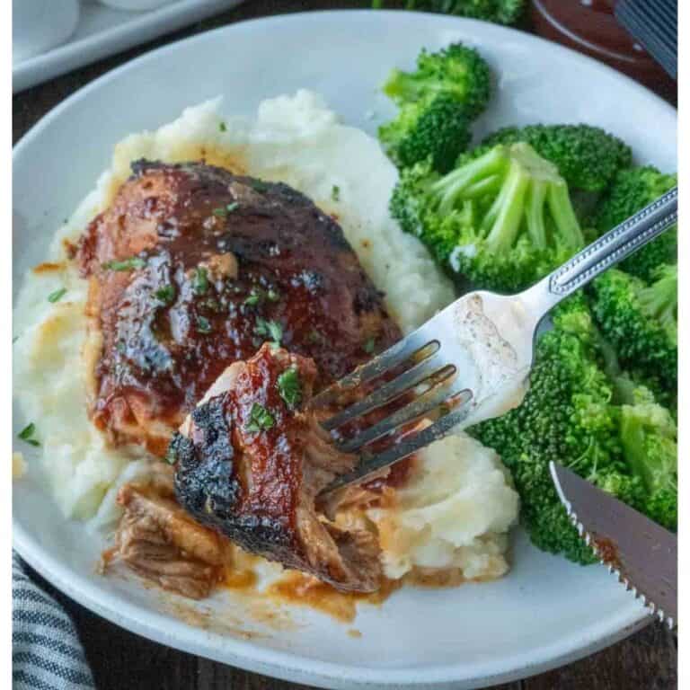 Bbq chicken thigh on a plate with mashed potatoes and broccoli.