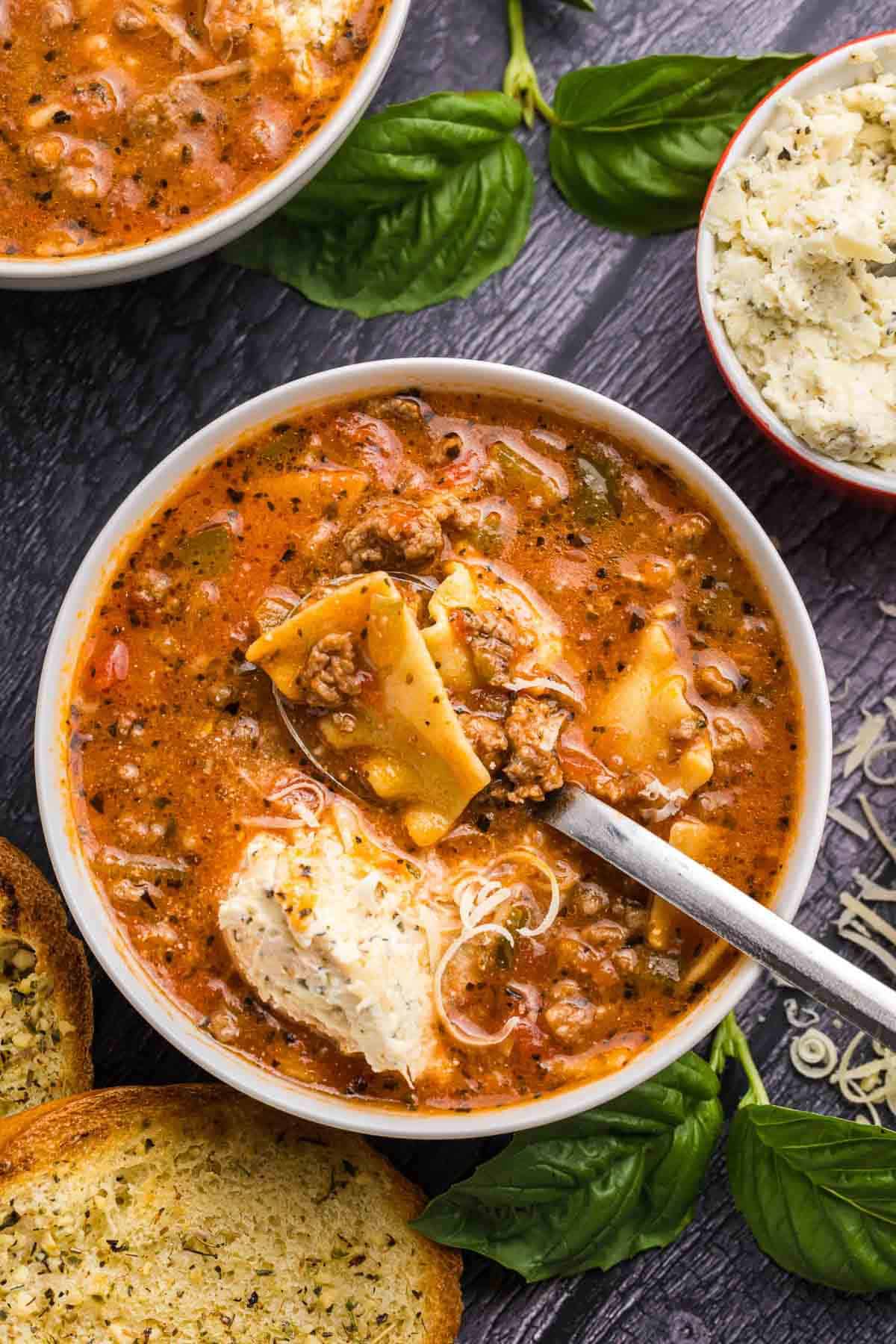 A bowl of lasagna soup with a large spoon.