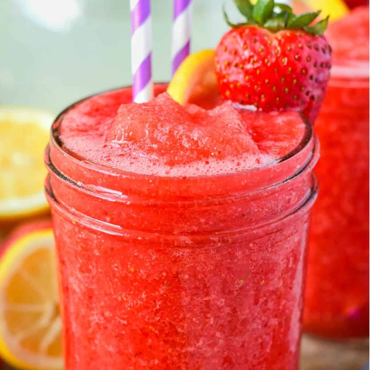 Cold red drink in a mason jar glass with two paper straws.
