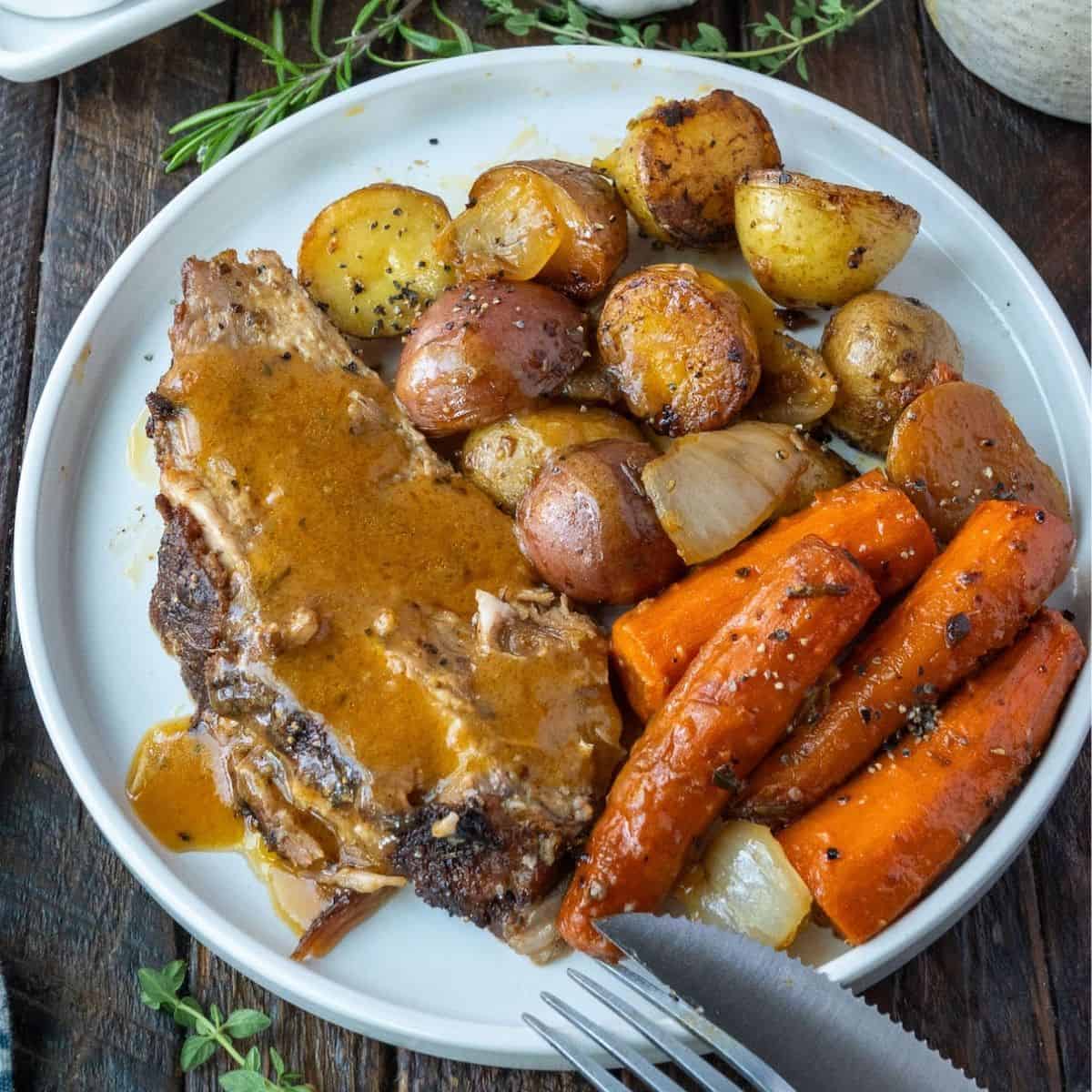 Pot roast on a plate with potatoes and carrots.